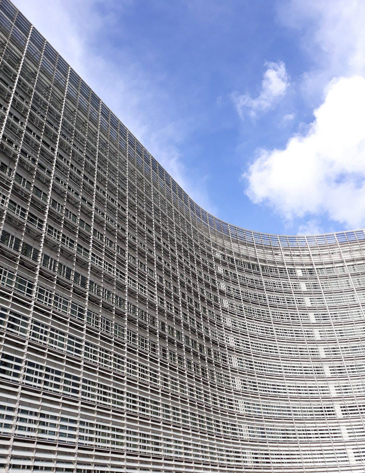 The curved glass facade of the Berlaymont building in Brussels against a blue sky