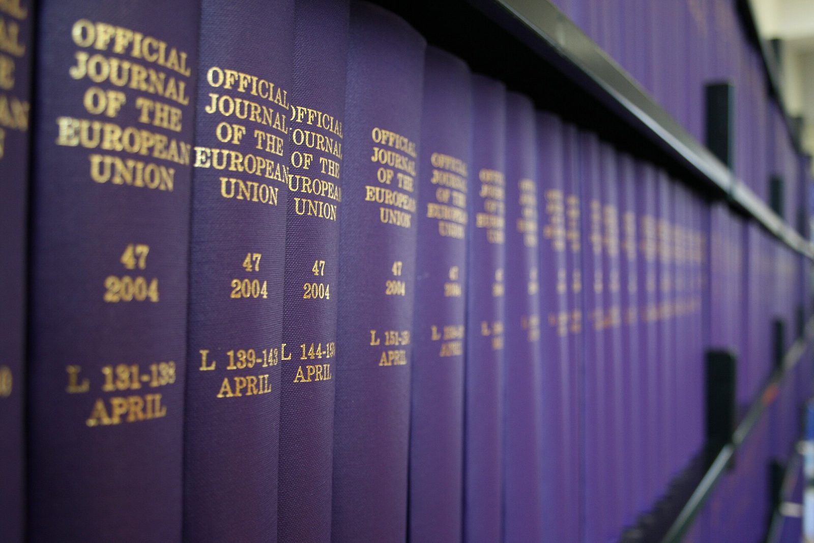 Rows of bound Official Journal volumes on a library shelf, their spines lettered in gold