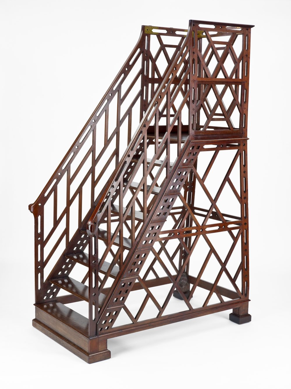 A mahogany library ladder of 1782, its open fretwork sides rising in steps to a railed platform